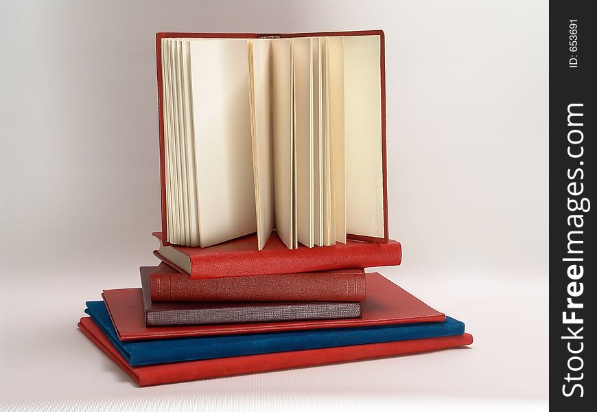 Composition with red books and one open book.
