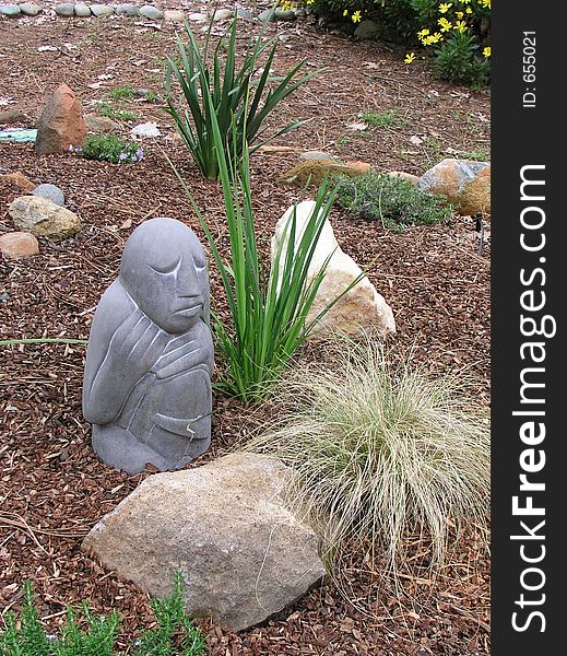 Contemplative, prayerful cement statue sits quietly in a small rocky garden area. Shot with my Olympus Cameda C-5050, 5mpx digital camera. Contemplative, prayerful cement statue sits quietly in a small rocky garden area. Shot with my Olympus Cameda C-5050, 5mpx digital camera.
