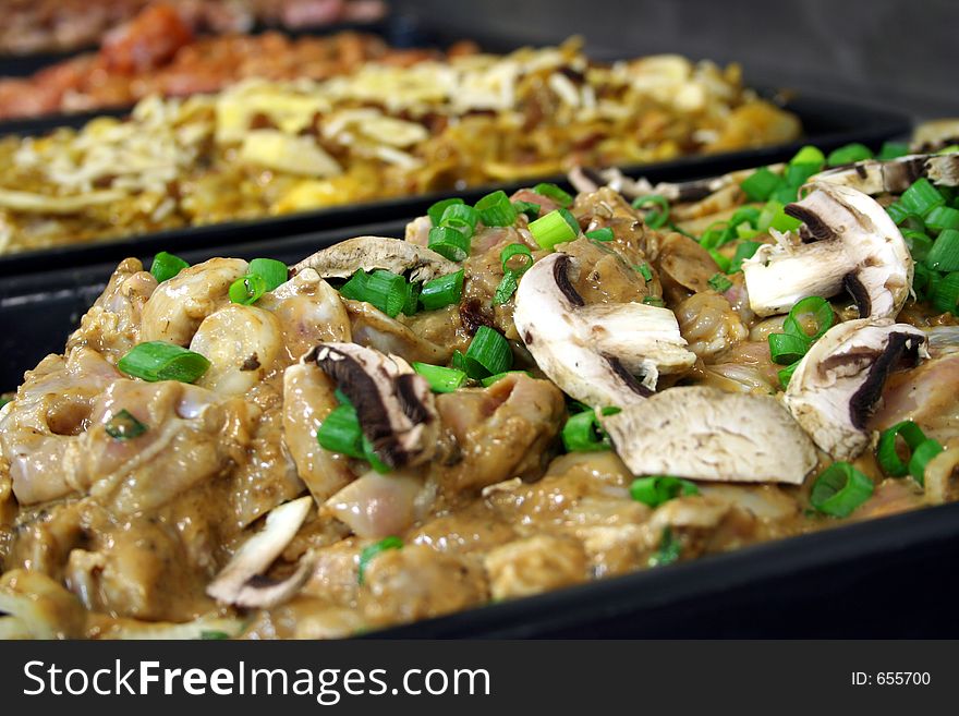 Several trays of different uncooked chicken mixtures freshly prepared close up. Several trays of different uncooked chicken mixtures freshly prepared close up