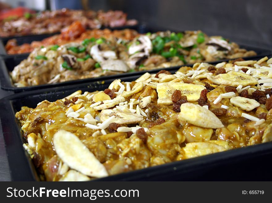 Several trays of different uncooked chicken mixtures freshly prepared. Several trays of different uncooked chicken mixtures freshly prepared