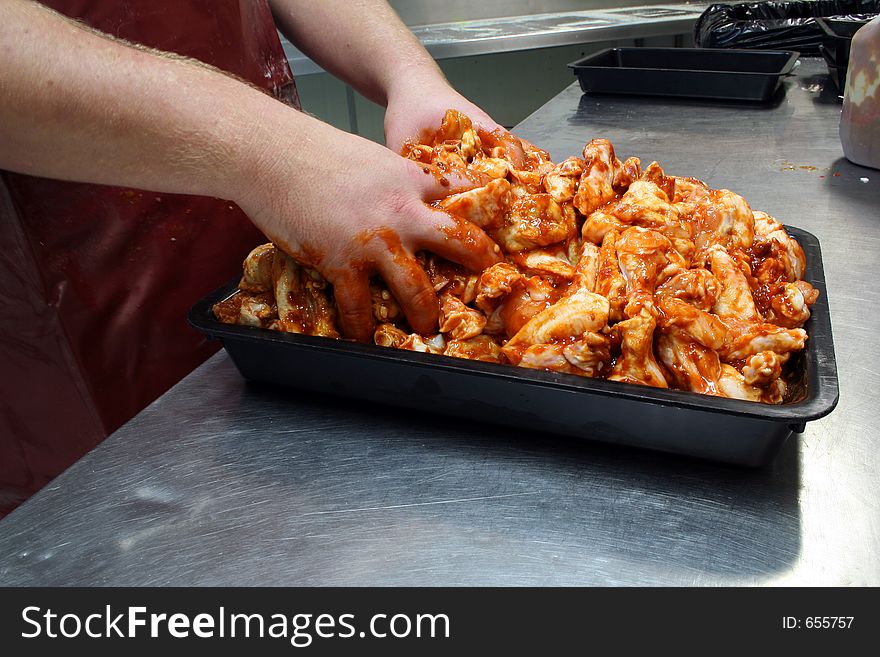 Chicken wings being prepared with satay sauce - hand mixed ready for sale. Chicken wings being prepared with satay sauce - hand mixed ready for sale