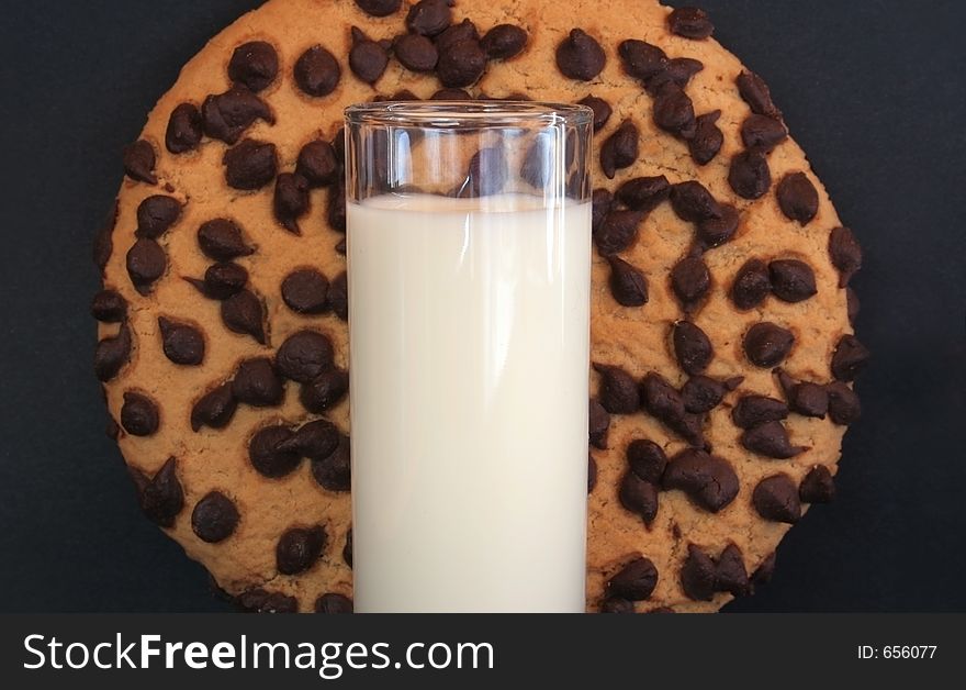 Image of a giant chocolate cookie dwarfing a glass of milk. Image of a giant chocolate cookie dwarfing a glass of milk