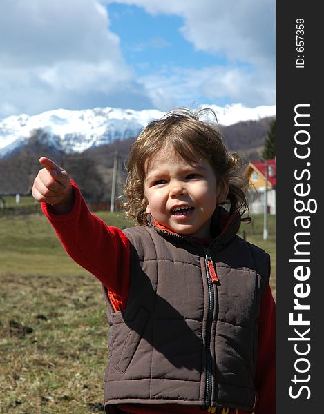 Young girl pointing towards something that caught her attention. Shot in early spring, mountain scenery in the background. Young girl pointing towards something that caught her attention. Shot in early spring, mountain scenery in the background.