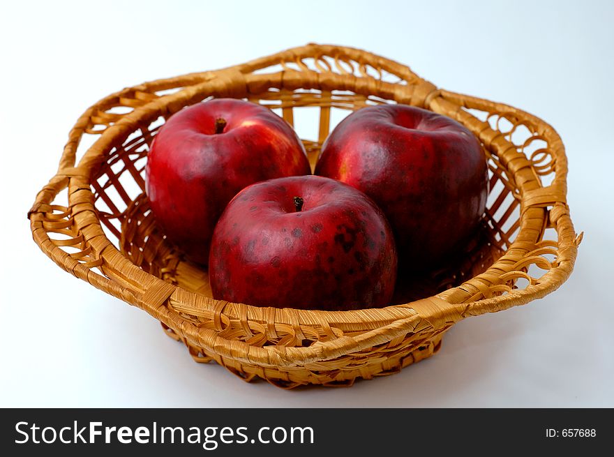 Three red apples in basket