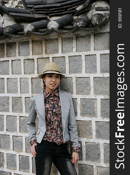 Stylish Asian girl leaning against a wall