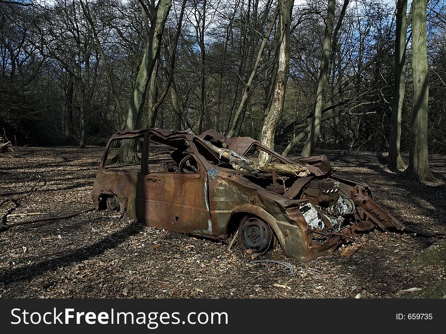 An abandoned burned out car in the woods