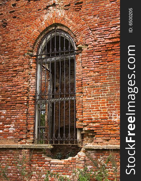 Ancient brick wall with window and iron lattice