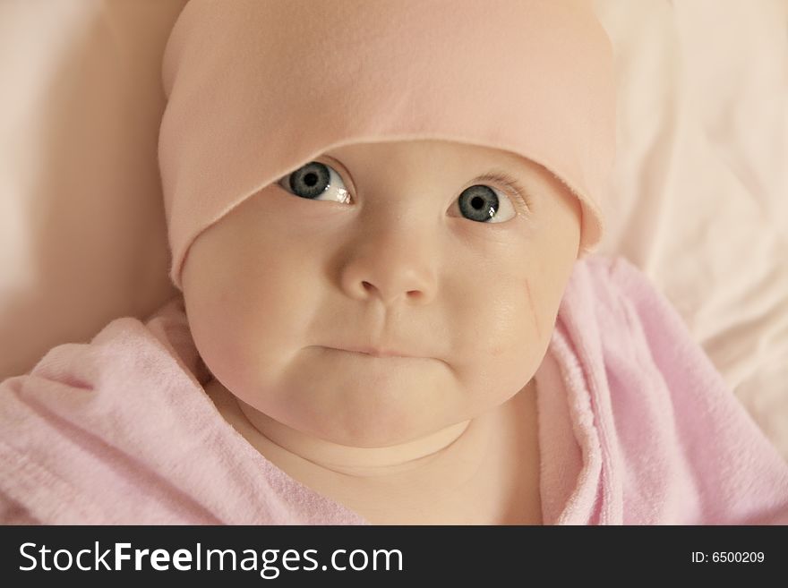 Cute big-eyed baby girl looking up with curious facial expression, space for text