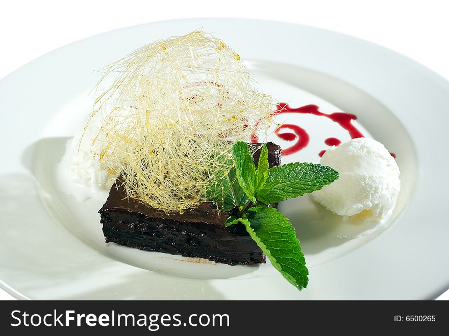 Chocolate dessert and icecream decorated with strands of burned sugar and mint leaves isolated on white