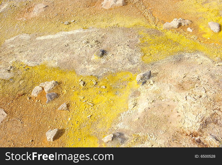 Colorful suplhur landscape. Small rocks lying around. Orange yellow soil.