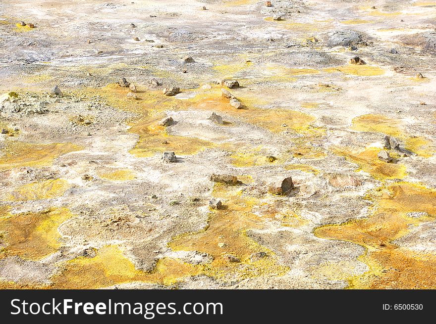 Colorful suplhur landscape. Small rocks lying around. Orange yellow soil.