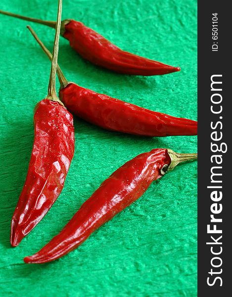 Four hot red chili paprika on a green cover