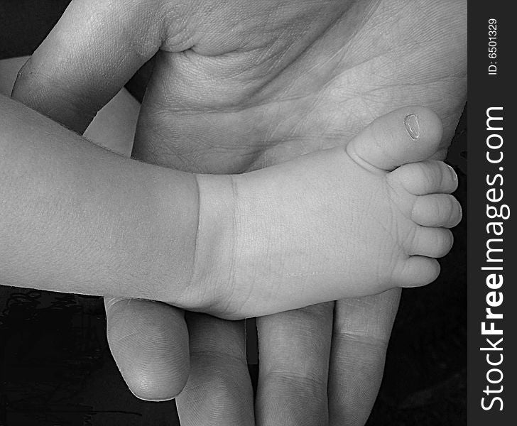 Small babyfoot in the hand of the father. Small babyfoot in the hand of the father