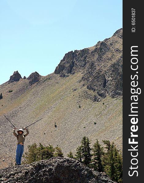 A young woman with hiking poles in the air celebrating her climbing victory.  California, U.S.A. A young woman with hiking poles in the air celebrating her climbing victory.  California, U.S.A.