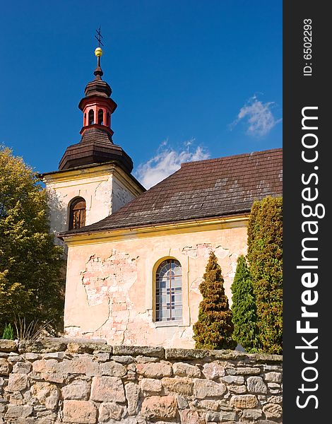 Old countryside church under Bezdez castle wit stony wall and trees, Czech Republic, Europe