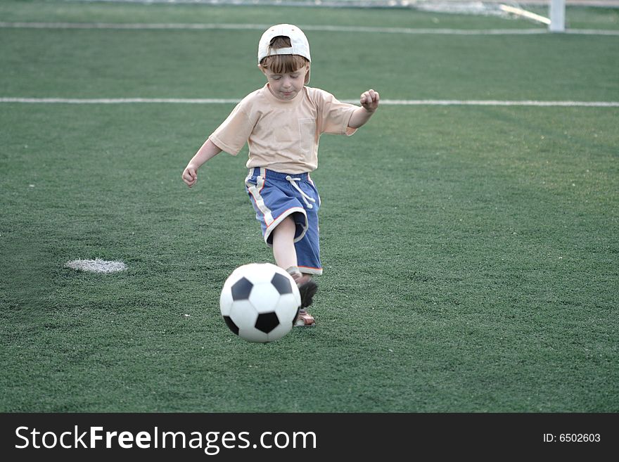 The kid hazardously playing football in stadium