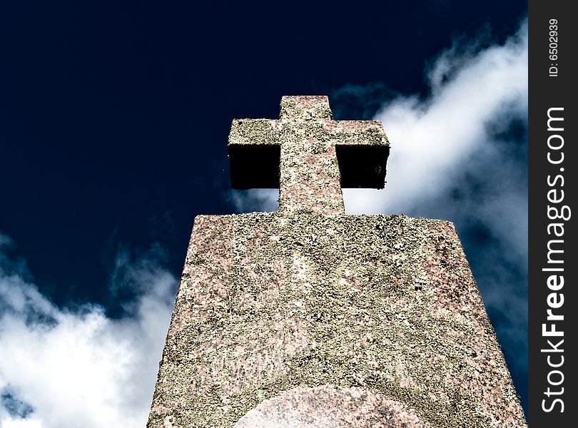 Old cemetery monument with a cross isolated on a deep blue dramatic sky