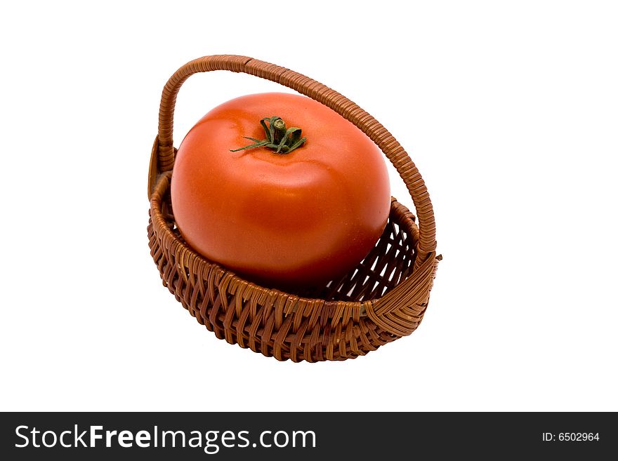 A single fresh red tomato in small wicker basket on isolated white background. A single fresh red tomato in small wicker basket on isolated white background