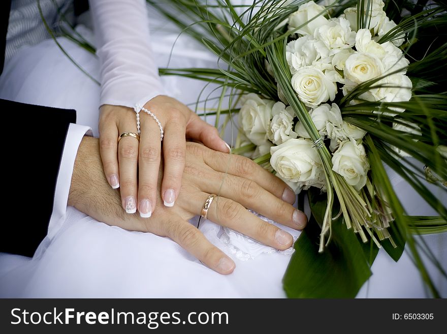 Holding hands of bride and groom with wedding bouquet in the background. Holding hands of bride and groom with wedding bouquet in the background