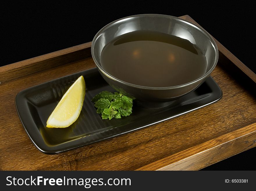 Tea in black cup with a slice of lemon