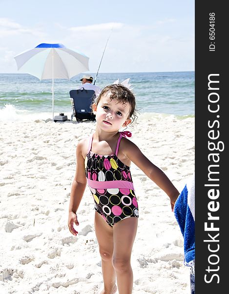 Cute little girl standing in the sand by the ocean in her swimsuit. Cute little girl standing in the sand by the ocean in her swimsuit.