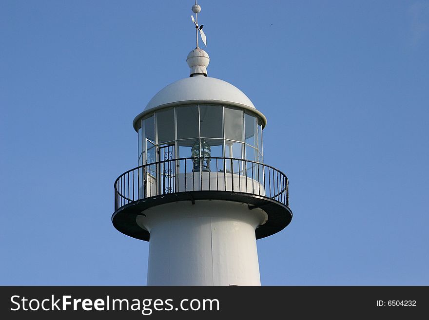 Top of lighthouse with windvane and a bird on top. closeup of freznel lens. balcony around the light. Top of lighthouse with windvane and a bird on top. closeup of freznel lens. balcony around the light