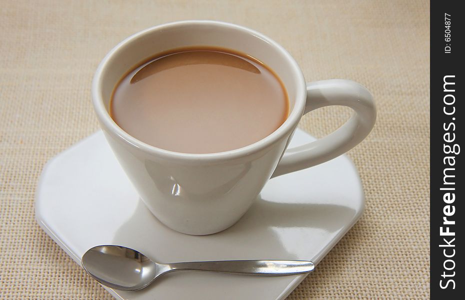 Milk coffee on white cup with the small spoon. Milk coffee on white cup with the small spoon