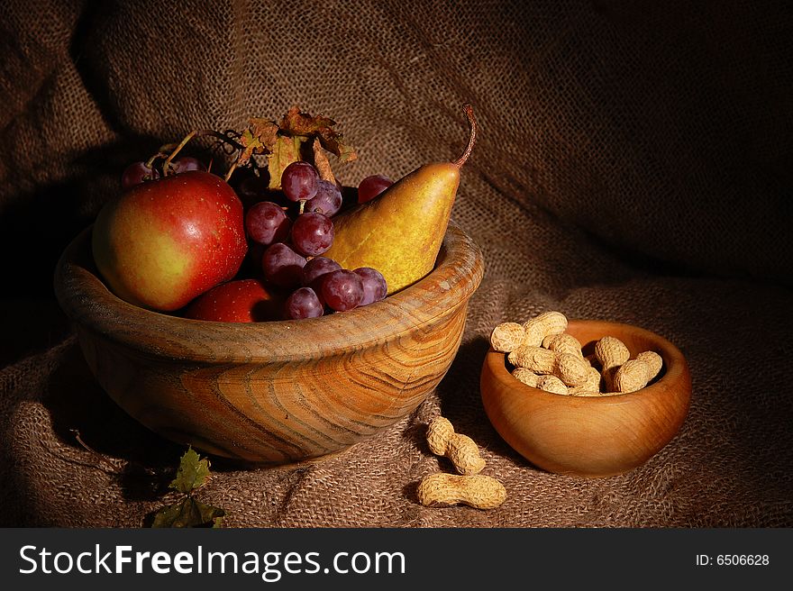 Autumn fruits in wooden cup on burlap background