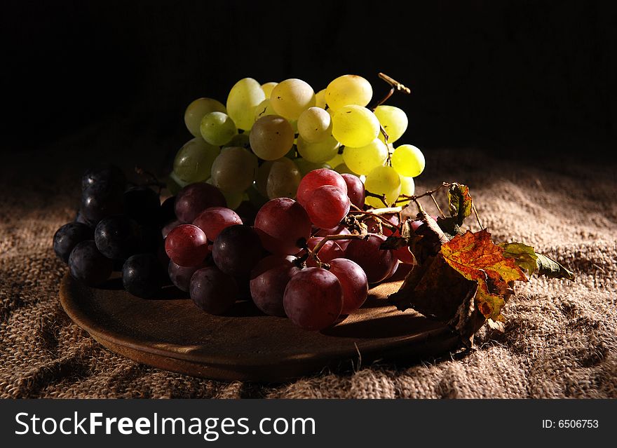 Grapes in wooden cup on burlap background