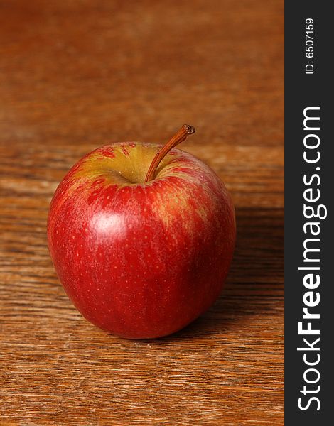 Portrait solitary large red apple on timber table