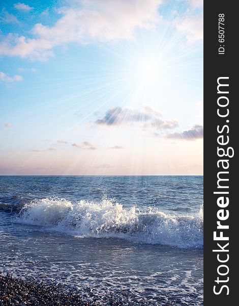 Bright sunbeams illuminate beautiful sea beachWave on sea beach under year blue sky and cloud