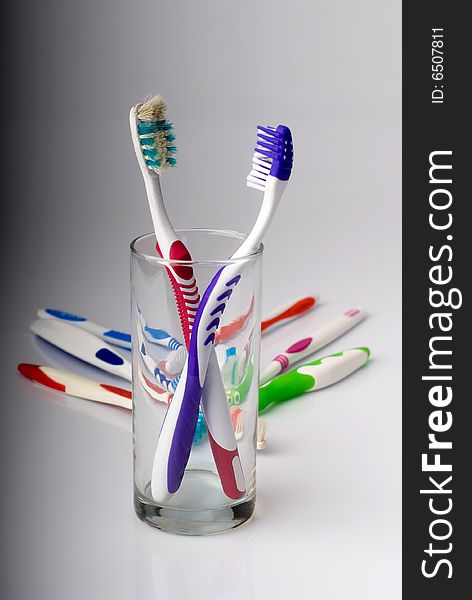 New and old toothbrushes in glass