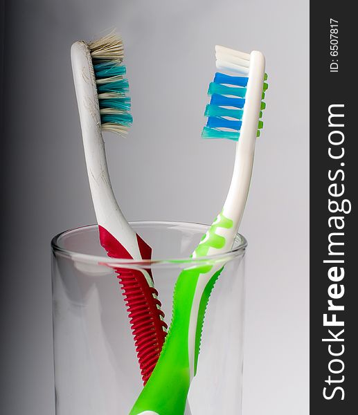 New and old toothbrushes in glass