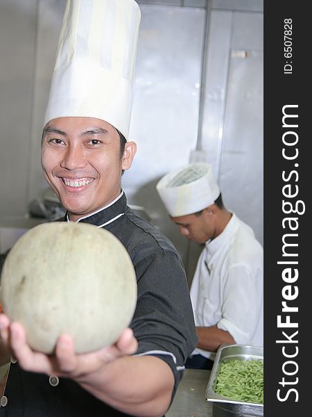 Chef holding honeydew melon at kitchen smiling