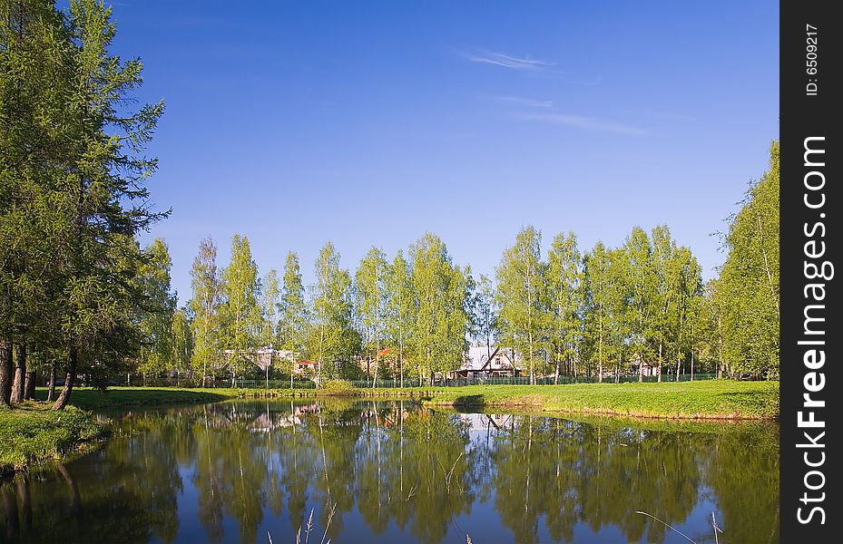 Lanscape with houses near lake under blue sky