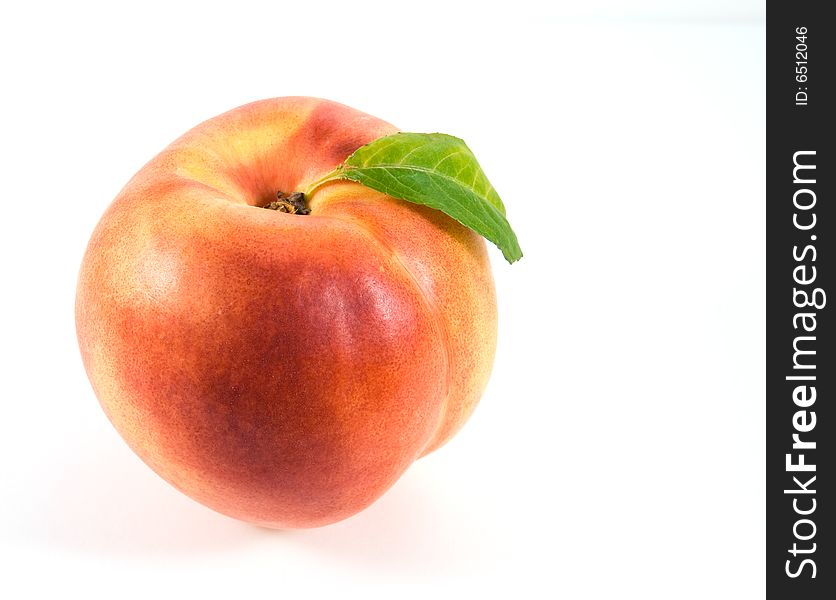 Ripe nectarine with green leaf on white background