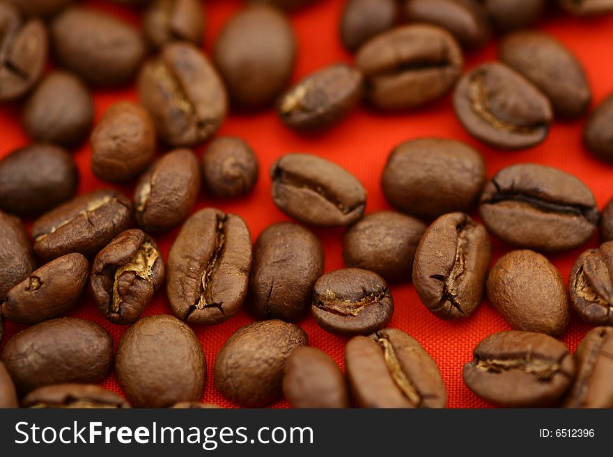 Coffee beans on red background, close up