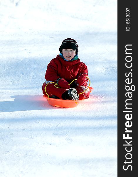 Boy in red in sled going downhill
