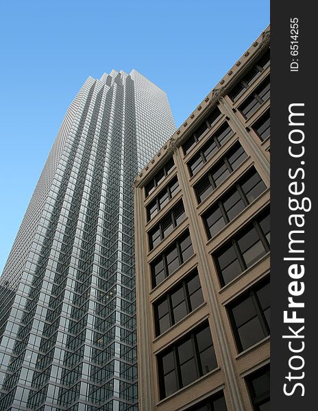 An older building stands in the foreground of a tall modern skyscraper. An older building stands in the foreground of a tall modern skyscraper.