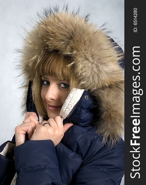 A smiling girl in a winter jacket with a hood edged by fur