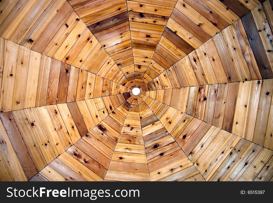 The ceiling of a wooden gazebo resembles a spiderweb pattern. The ceiling of a wooden gazebo resembles a spiderweb pattern