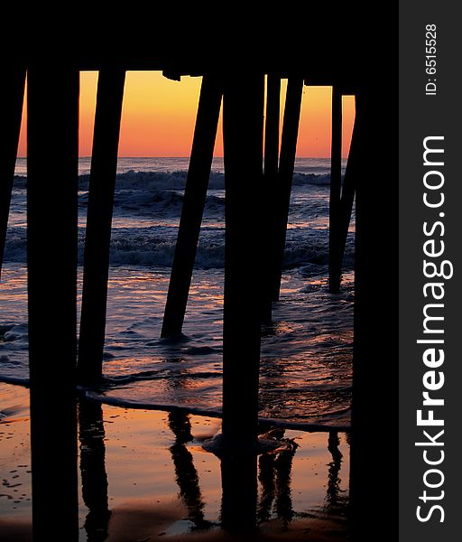 An interesting angle of the sunrise from under a pier as the waves reflect the sunlight. An interesting angle of the sunrise from under a pier as the waves reflect the sunlight.