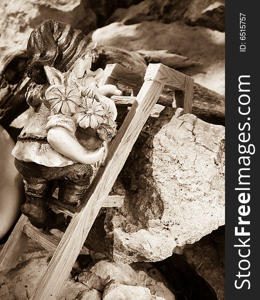 A Ceramic Garden Gnome climbing a ladder among the stones.