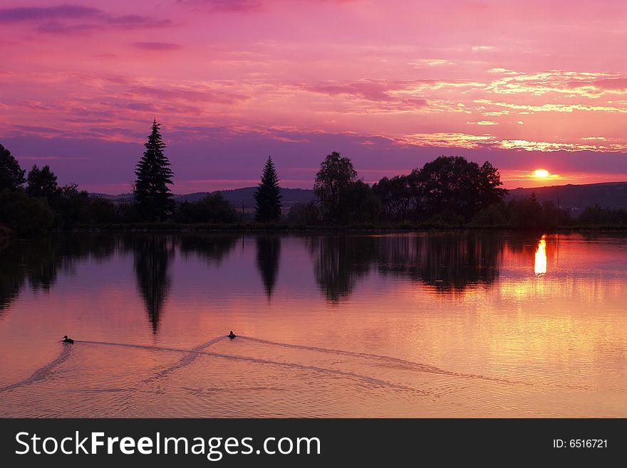 Violet colored sunset by pond