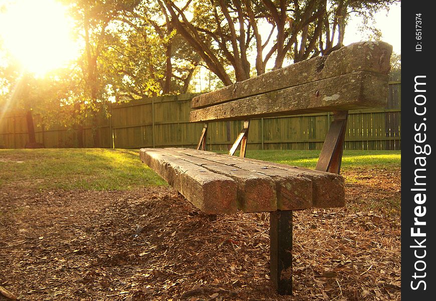 Empty wooden bench in park with sun setting behind it. Empty wooden bench in park with sun setting behind it