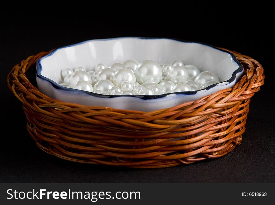 Basket with white pearls isolated on a black background