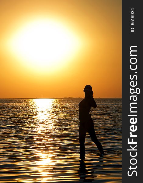 Silhouette of the young woman on a bay on a sunset