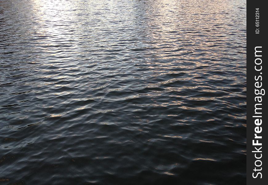 Light Reflecting On Water In A Pond During Sunset In Winter.