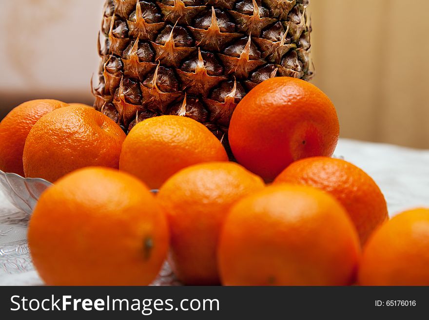 Orange tangerines and pineapple on the table closeup