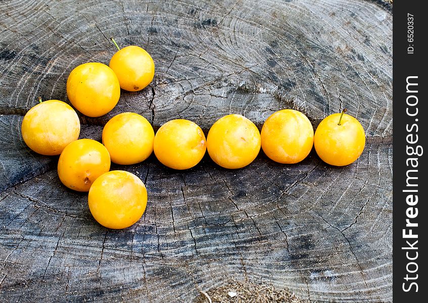 Arrow poining left made with yellow plums on wood surface. Arrow poining left made with yellow plums on wood surface